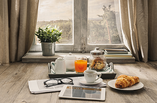 Frühstück mit Zeitung vor einem Fenster