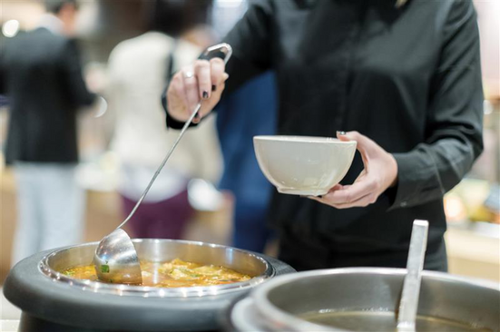 Suppe wird aus einem Suppenkessel geschöpft