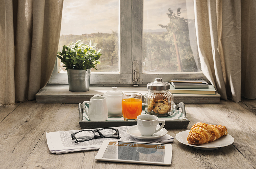 Frühstück mit Zeitung vor einem Fenster