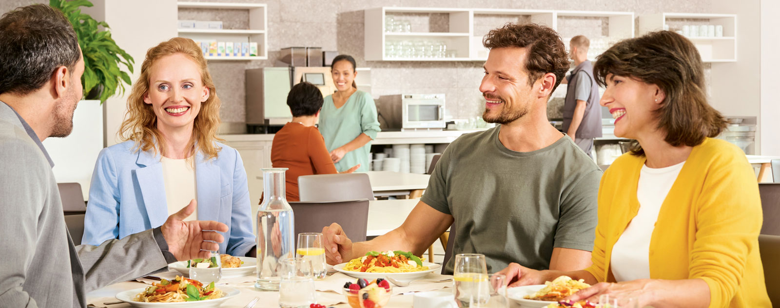 Team sitzt gemeinsam beim Mittagessen im Büro